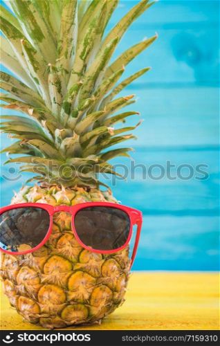 Holiday pineapple have sunglasses on blue wooden background, tropical holiday concept