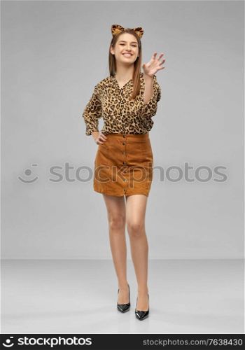 holiday, theme party and people concept - happy smiling woman in halloween costume of leopard with ears over grey background. happy woman in halloween costume of leopard