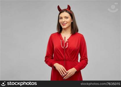 holiday, theme party and people concept - happy smiling woman in red halloween costume of devil with horns and trident over grey background. happy woman in red halloween costume of devil