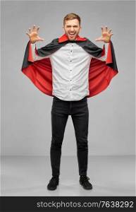 holiday, theme party and people concept - man in halloween costume of vampire and dracula cape scaring over grey background. man in halloween costume of vampire scaring