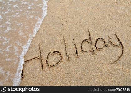 Holiday word written on sandy beach