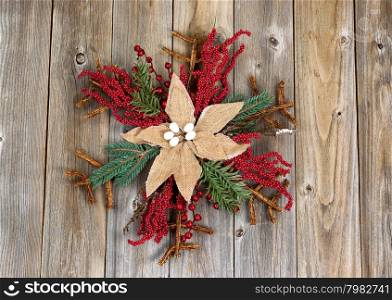 Holiday wreath, cloth flower in center, on rustic wood. Layout in horizontal format.