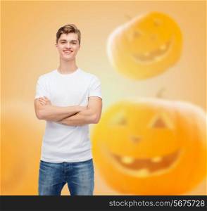 holidays, advertisement and people concept - smiling young man in blank white t-shirt over halloween pumpkins background
