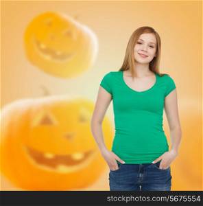 holidays, advertisement and people concept - smiling young woman in blank green t-shirt over halloween pumpkins background