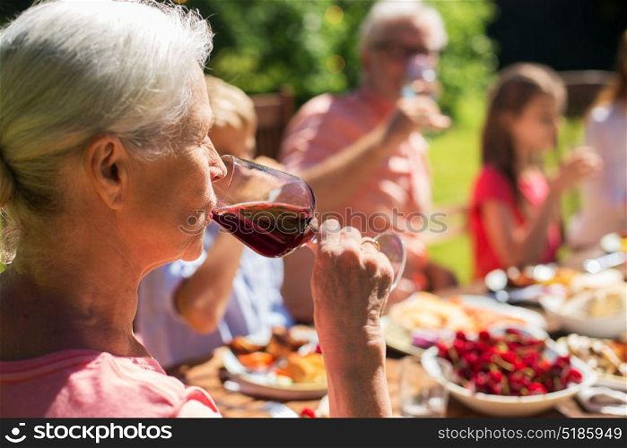 holidays, alcohol and people concept - senior woman drinking red wine at family festive dinner or summer garden party. senior woman drinking wine at family dinner