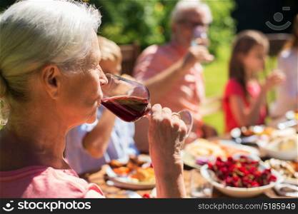 holidays, alcohol and people concept - senior woman drinking red wine at family festive dinner or summer garden party. senior woman drinking wine at family dinner