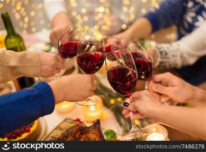 holidays and celebration concept - close up of friends having christmas dinner at home, drinking red wine and clinking glasses. close up of friends with wine celebrate christmas