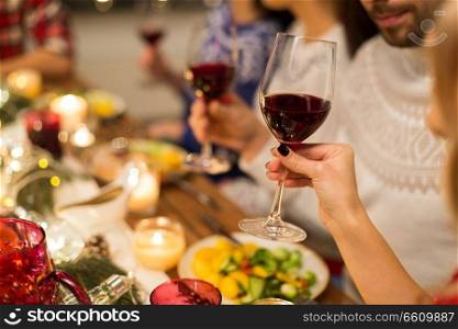 holidays and celebration concept - close up of happy friends having christmas dinner and drinking red wine. close up of friends drinking red wine on christmas