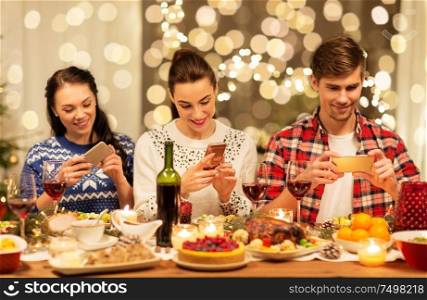 holidays and celebration concept - happy friends having christmas dinner at home and photographing food by smartphone. happy friends having christmas dinner at home