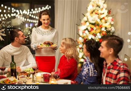 holidays and celebration concept - happy friends having christmas dinner at home. happy friends having christmas dinner at home