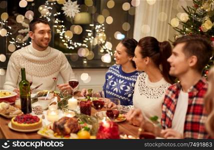 holidays and celebration concept - happy friends having christmas dinner at home and eating. happy friends having christmas dinner at home