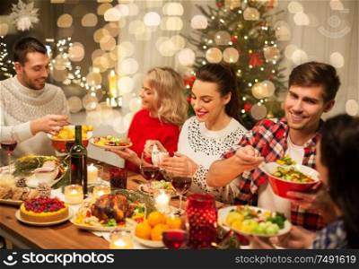 holidays and celebration concept - happy friends having christmas dinner at home and eating food. happy friends having christmas dinner at home