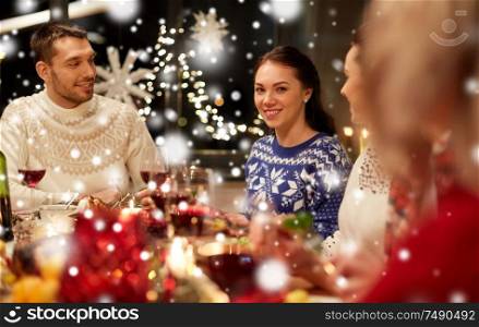 holidays and celebration concept - happy friends having christmas dinner at home and eating over snow. happy friends having christmas dinner at home