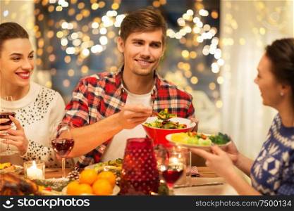holidays and celebration concept - happy friends having christmas dinner at home, eating and drinking. happy friends having christmas dinner at home