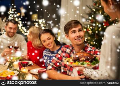 holidays and celebration concept - happy friends having christmas dinner at home over snow. happy friends having christmas dinner at home