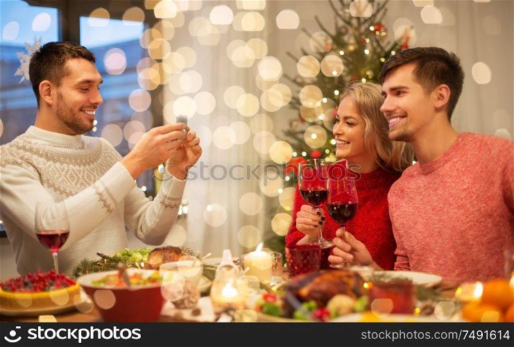 holidays and celebration concept - happy friends photographing at christmas dinner. happy friends photographing at christmas dinner