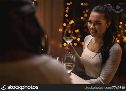 holidays and celebration concept - happy woman having christmas dinner at home and drinking white wine. happy woman drinking wine at christmas dinner