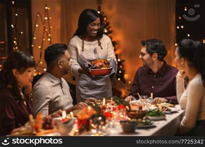 holidays and celebration concept - multiethnic group of happy friends having christmas dinner at home. happy friends having christmas dinner at home