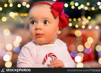 holidays and childhood concept - beautiful baby girl over christmas tree lights. beautiful baby girl over christmas tree lights