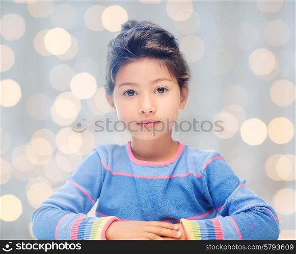 holidays and children concept - little student girl over holidays lights background