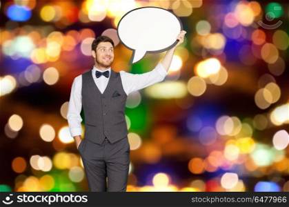 holidays and communication concept - happy man in suit holding blank text bubble banner over festive lights background. man with blank text bubble banner over lights . man with blank text bubble banner over lights