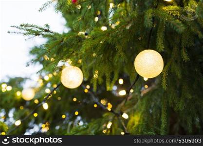 holidays and decoration concept - close up of christmas tree garland bulbs outdoors. close up of christmas tree garland bulbs outdoors