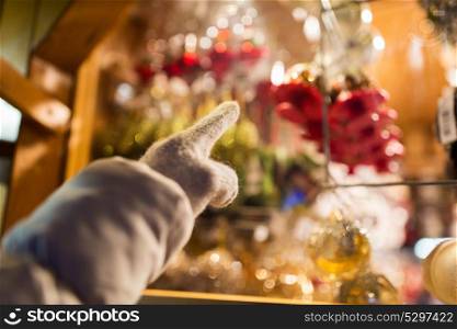 holidays and decoration concept - close up of hand pointing at christmas toys behind shop window. hand pointing at christmas toys behind shop window