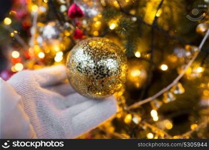 holidays and decoration concept - close up of hand with christmas tree toy at fir. close up of hand with christmas tree toy