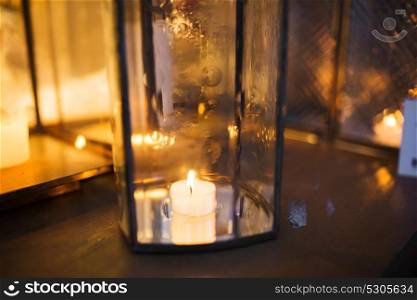 holidays and decoration concept - close up of lantern with candle burning inside. close up of lantern with candle burning inside