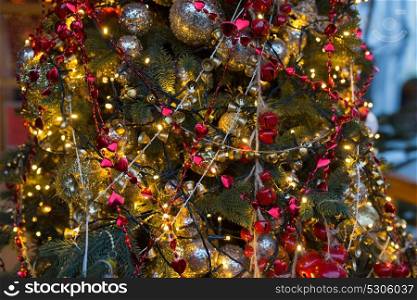 holidays and decoration concept - close up of natural fir with christmas tree toys and garlands outdoors. close up of fir with christmas tree toys outdoors