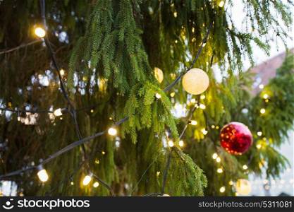 holidays and decoration concept - close up of natural fir with christmas tree toys and garlands outdoors. close up of fir with christmas tree toys outdoors
