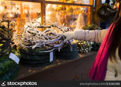 holidays and decoration concept - close up of woman with branch wreath at christmas market stall. woman with branch wreath at christmas market
