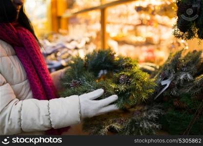 holidays and decoration concept - close up of woman with fir tree wreath at christmas market stall. woman with fir tree wreath at christmas market