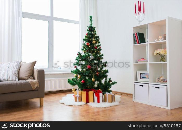 holidays and interior concept - artificial christmas tree and presents at home living room. artificial christmas tree and presents at home
