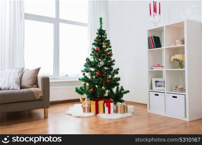 holidays and interior concept - artificial christmas tree and presents at home living room. artificial christmas tree and presents at home