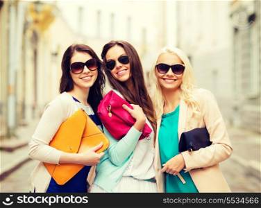 holidays and lifestyle concept - beautiful girls with bags in the ctiy