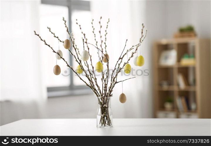 holidays and object concept - pussy willow branches decorated by easter eggs in vase on table. pussy willow branches decorated by easter eggs