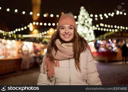 holidays and people concept - beautiful happy young woman at christmas market in winter evening. happy young woman at christmas market in winter