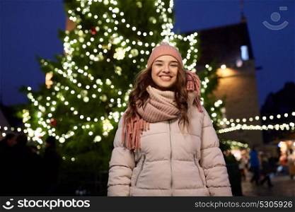 holidays and people concept - beautiful happy young woman at christmas tree in winter evening. happy young woman at christmas market in winter
