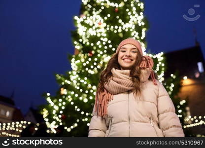 holidays and people concept - beautiful happy young woman at christmas tree in winter evening. happy young woman at christmas in winter
