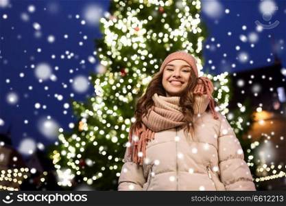 holidays and people concept - beautiful happy young woman at christmas tree in winter evening. happy young woman at christmas in winter
