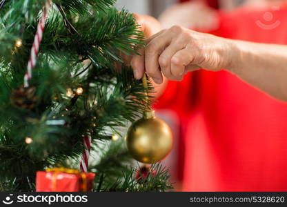 holidays and people concept - close up of happy senior woman decorating christmas tree. close up of senior woman decorating christmas tree