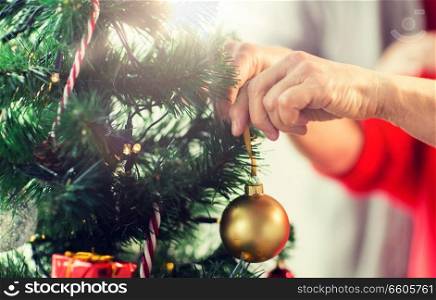 holidays and people concept - close up of happy senior woman decorating christmas tree. close up of senior woman decorating christmas tree