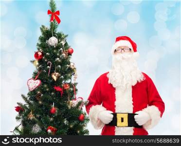 holidays and people concept concept - man in costume of santa claus with christmas tree over blue lights background