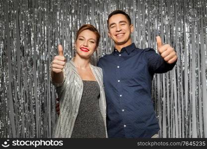 holidays and people concept - happy hugging couple in party clothes showing thumbs up. couple in party clothes showing thumbs up