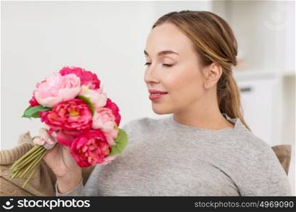 holidays and people concept - happy young woman smelling flowers at home. happy woman smelling flowers at home