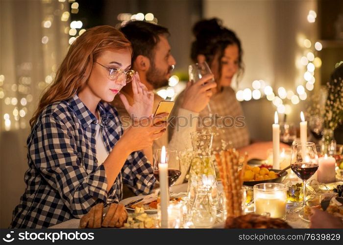 holidays and people concept - woman with smartphone at dinner party with friends at home. woman with smartphone at dinner party with friends