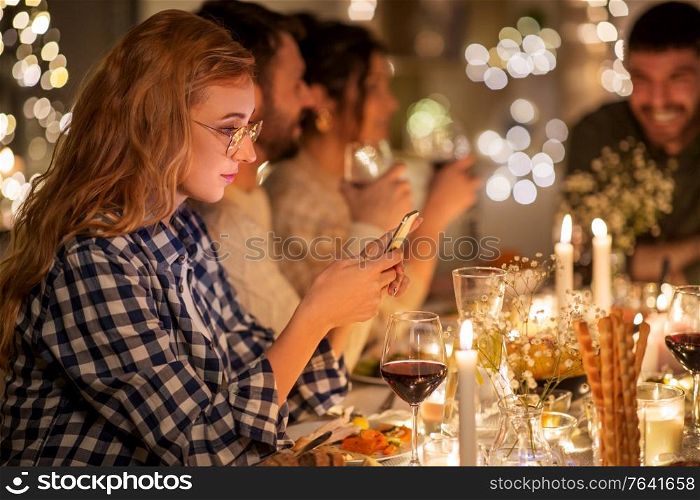 holidays and people concept - woman with smartphone at dinner party with friends at home. woman with smartphone at dinner party with friends
