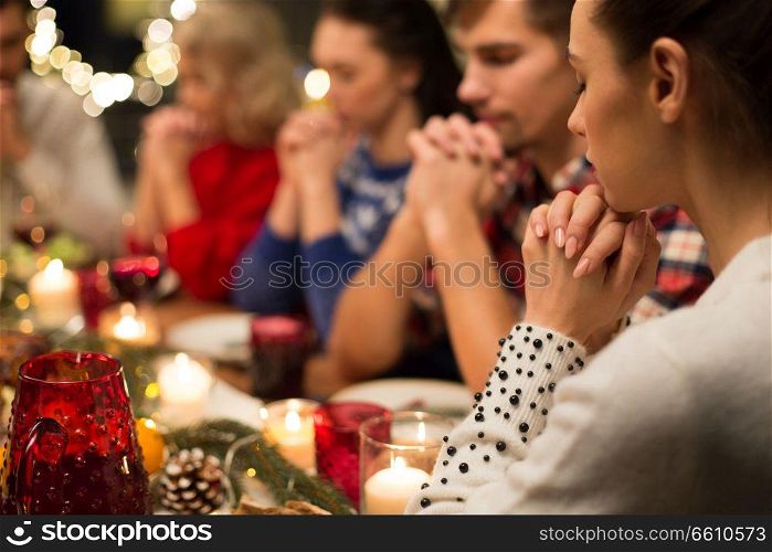 holidays and religious concept - close up of friends having christmas dinner and praying before meal. close up of friends praying at christmas dinner