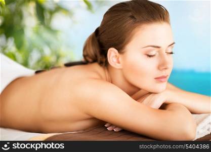 holidays and spa concept - beautiful woman in spa salon with hot stones